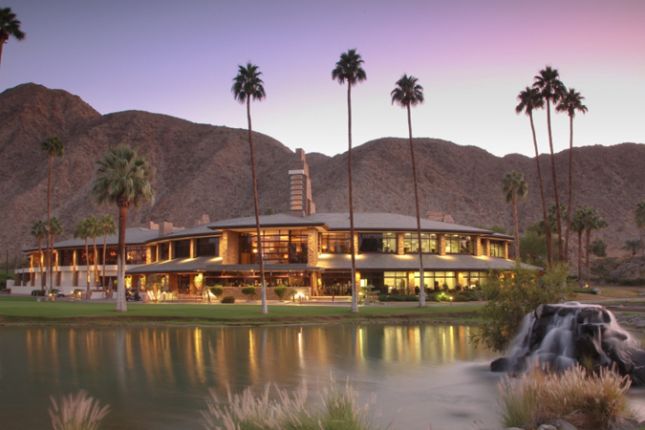 Gated community entrance monument sign in Indian Wells with palm trees and desert landscaping