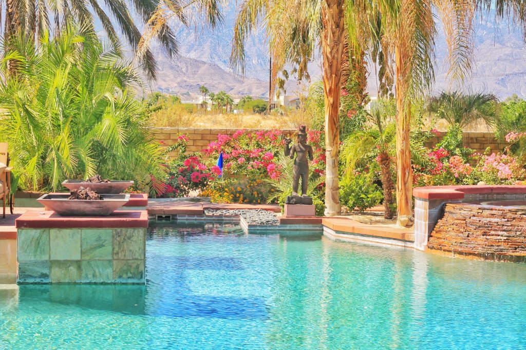 Gated residential entry in Palm Springs with palm-lined landscaping and mountain views